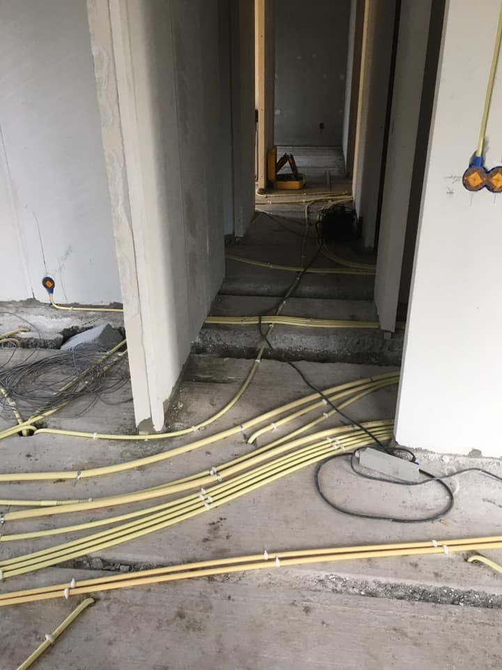 Gele installatiebuizen in bundels over een betonvloer in een nieuwbouwwoning